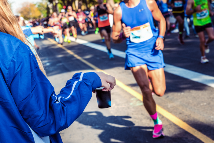 Marathon runner collecting a cup of water from their support